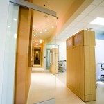 Clinic hallway with glass doors, wood cabinet, and visible treatment room.