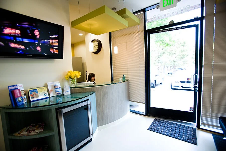 Reception desk with TV, mini-fridge, and glass door to street.