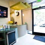 Reception desk with TV, mini-fridge, and glass door to street.