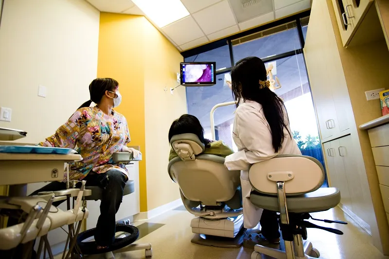 Dental team consulting with child patient in treatment room