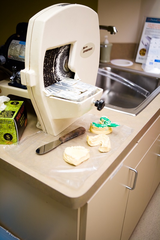 Dental model trimmer on counter with trimmed stone models and tools